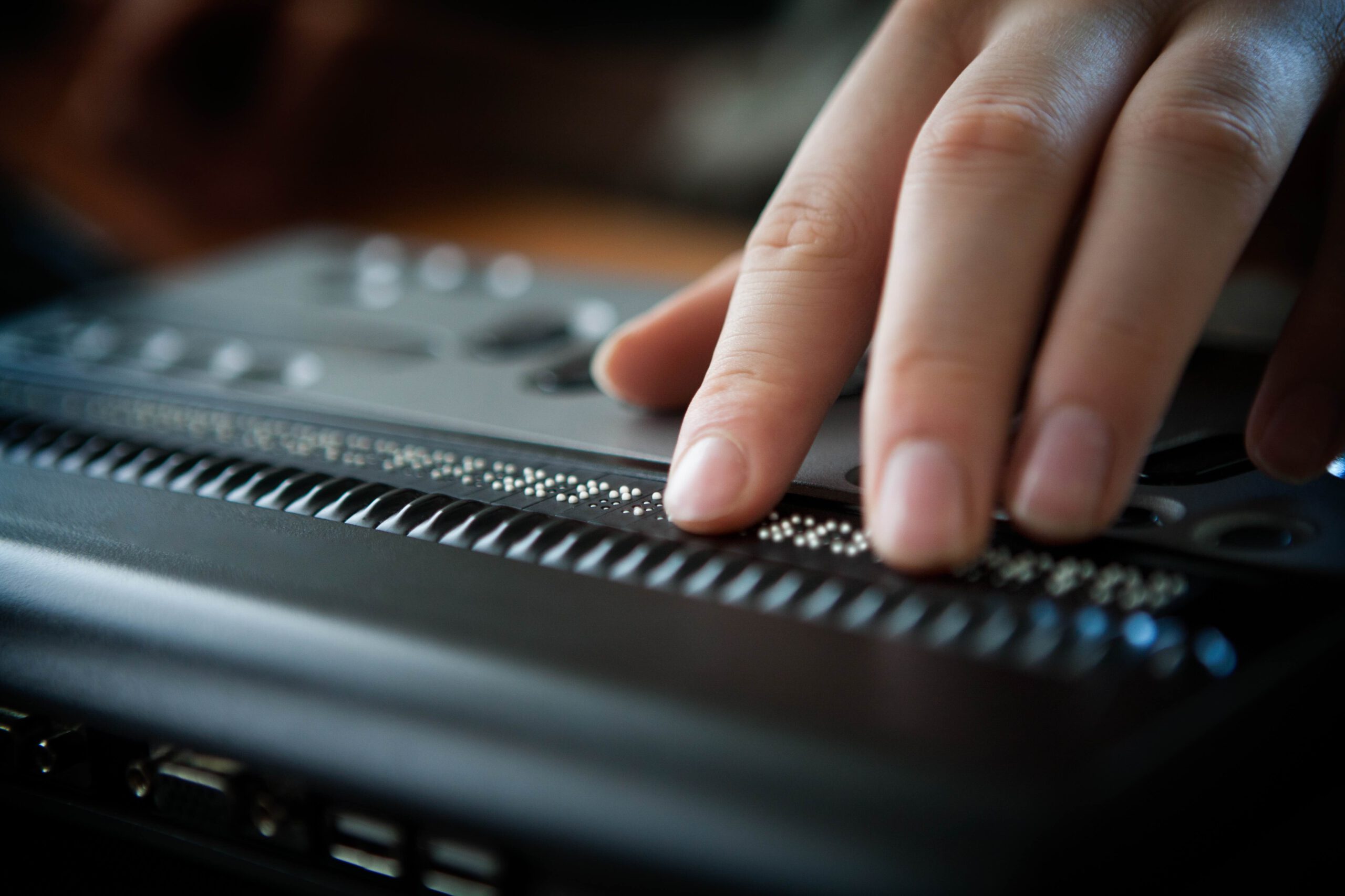 Dargestellt ist eine Hand, die eine Braille-Zeile bedient.